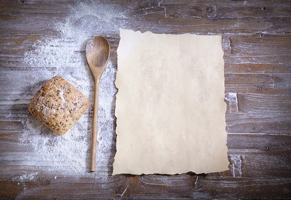 Pain au sésame, farine éparpillée, cuillère et papier cuisson — Photo