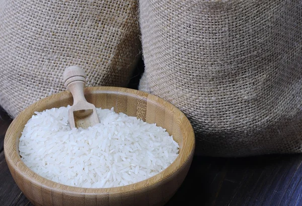 Белый рис в миске против двух текстильных мешков — стоковое фото