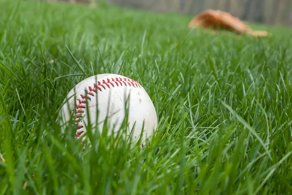 Honkbal in gras met handschoen achter — Stockfoto