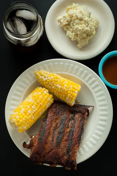 Barbecue varkensvlees Spare Ribs met maïs en aardappelsalade Stockafbeelding