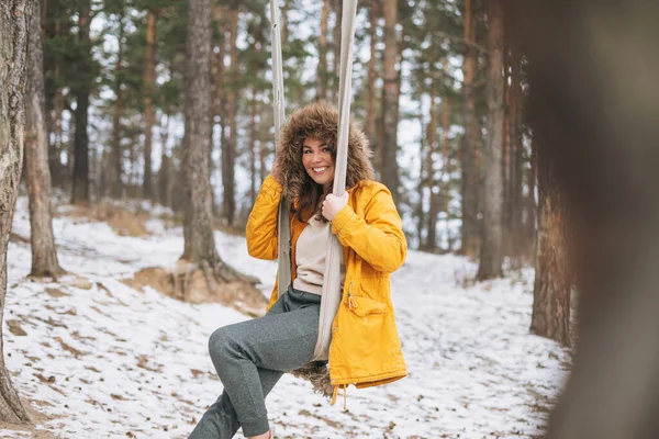 Młoda Beztroska Kobieta Żółtej Kurtce Huśta Się Huśtawce Zimowym Lesie — Zdjęcie stockowe