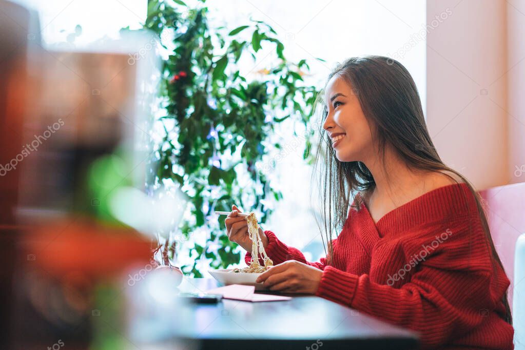 Beautiful smiling young asian woman in red clothes eating asian food in chinese vietnamese restaurant