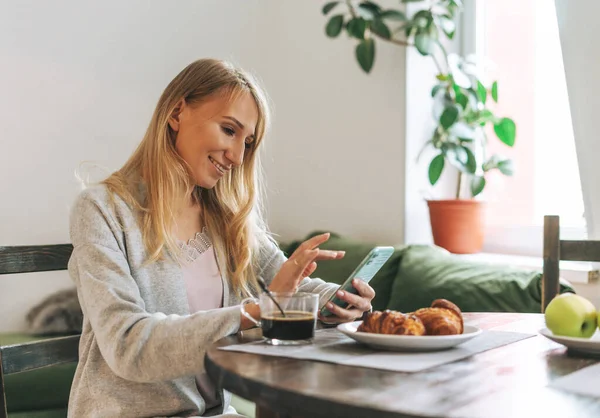 Mooie Blonde Jonge Vrouw Ontbijten Met Behulp Van Mobiele Woonkamer — Stockfoto