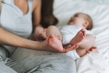 Young mother having fun with cute baby girl on bed, natural tones, selective focus