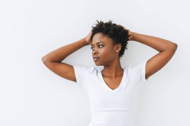 Beyaz arka planda izole edilmiş beyaz tişörtlü güzel Afro-Amerikan kadın portresi.