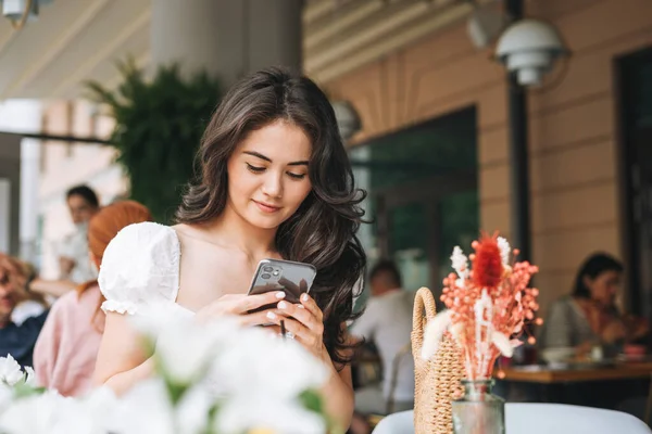 Улыбающаяся Красивая Брюнетка Молодая Женщина Белой Одежде Мобильного Телефона Столе — стоковое фото