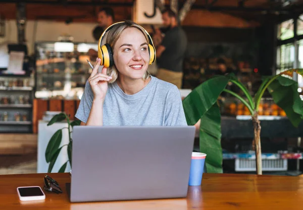 Junge Lächelnde Blonde Freiberuflerin Mit Gelben Kopfhörern Laptop Auf Dem — Stockfoto