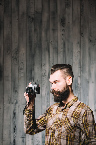 Bearded man takes photo with vintage film camera