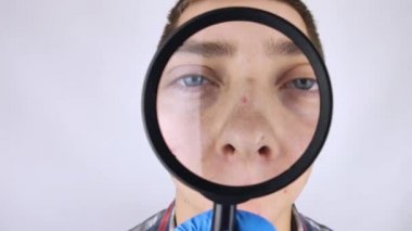 Sivilce ve siyah noktalar yakın plan. Bir adam bir doktor tarafından muayene ediliyor. Dermatolog deriyi büyüteçle inceliyor, büyüteçle.. 
