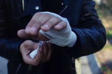 The fighter is bandaging his hands. The concept of preparation for a fight, sports competition, boxing and kickboxing. A man in a leather jacket.