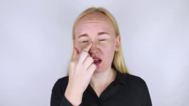 Burun köprüsü ağrısı, baş ağrısı. Bir kadın burnunu eliyle tutar ve acı içinde ürker. Akut etimoidit belirtileri. Bir doktorun muayenesinde..