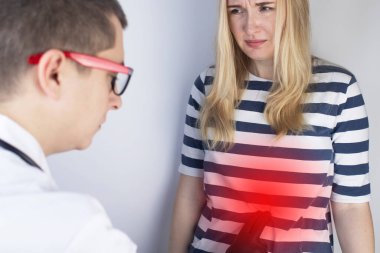 Bir kadın onun karnına tutunuyor. Karın boşluğunda bir ağrı var. Mide hastalıkları ve sindirim sistemi kavramı. Doktor acının kaynağını bulmak için muayene olacak.