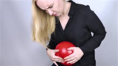 Şişkinlik ve gaz konsepti. Kadın karnının yanında şişkinliği sembolize eden kırmızı bir balon tutuyor. Bağırsak yolu ve sindirim sistemi. Osurma ve gastrointestinal sistemde sorun var.