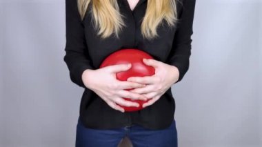 Şişkinlik ve gaz konsepti. Kadın karnının yanında şişkinliği sembolize eden kırmızı bir balon tutuyor. Bağırsak yolu ve sindirim sistemi. Osurma ve gastrointestinal sistemde sorun var.