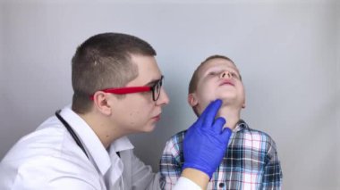 Bir çocuk doktoru boğaz ağrısından şikayet eden bir çocuğu muayene eder. Trakeal hastalıkların teşhisi. Anjin, bademcik iltihabı, gırtlak iltihabı, nazofarinkste ağrı. Çocuk tıbbi bakım konsepti