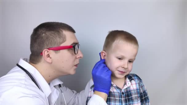 耳鼻咽喉科医は痛みを訴える少年の耳を調べる 痛みの軽減と治療の概念 耳の運河や鼓膜の炎症 小児科医の診察で — ストック動画