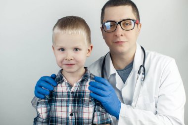Çocuk doktoru kucaklıyor. Çocuğu bir pediyatrist muayene etti. Çocuk koruma, sağlık ve tıbbi bakım konsepti. Beyaz arkaplanda yakın plan