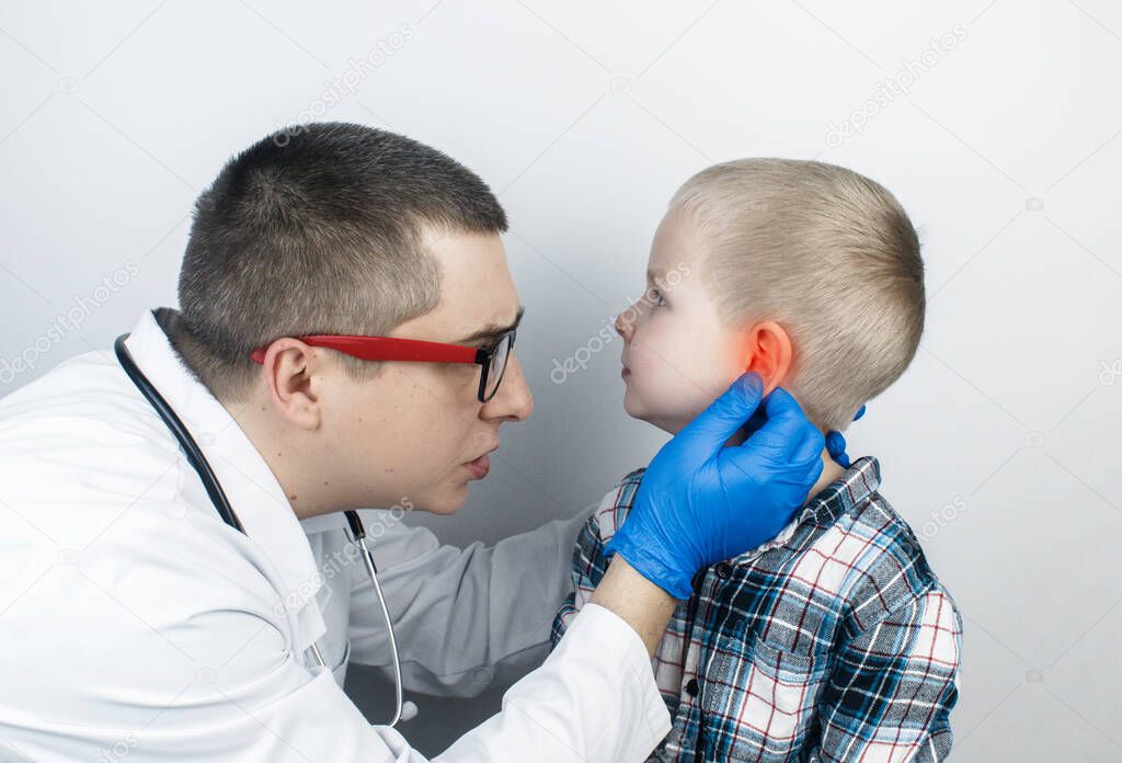 An otolaryngologist examines the ear of a boy who complains of pain. Pain relief and treatment concept. Inflammation of the ear canal or eardrum. On examination by a pediatrician.