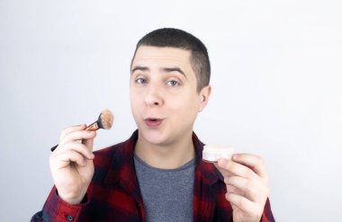 Adam çerçeveye bakar ve barut kullanır. Yüzüne makyaj yapan bir adamın yakın çekimi. LGBT topluluğu, gay ya da kendine bakım kavramı.