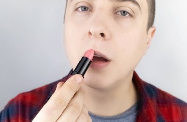 Dudaklarını boyayan bir adamın yakın çekimi. LGBT toplumunun haklarını koruma kavramı, homoseksüelliğin açık bir tezahürü ve erkeklerdeki kadın niteliklerinin dışavurumu.