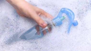 Köpükte bir şişe deterjan yüzüyor. Evdeki kimyasalların tehlikeleri kavramı. Köpükteki sodyum ödüllü maddeler, parabenler, sülfatlar ve diğer tehlikeli kimyasal bileşikler. Oda spreyi