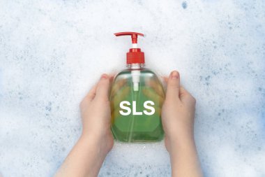 Sabunlu suda yüzen bir şişe sıvı sabun. Malzemelerin zararlı bileşimi, SLS içeren deterjan. Kozmetik ve ev kimyasallarında tehlikeli maddeler kavramı