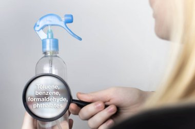 Bir kadın hava spreyinin zararlı bileşenlerini büyüteçle inceliyor. Toluen, benzen, formaldehit ve ftalat ile yapılır. Kozmetik ve ev kimyasallarında tehlikeli maddeler kavramı