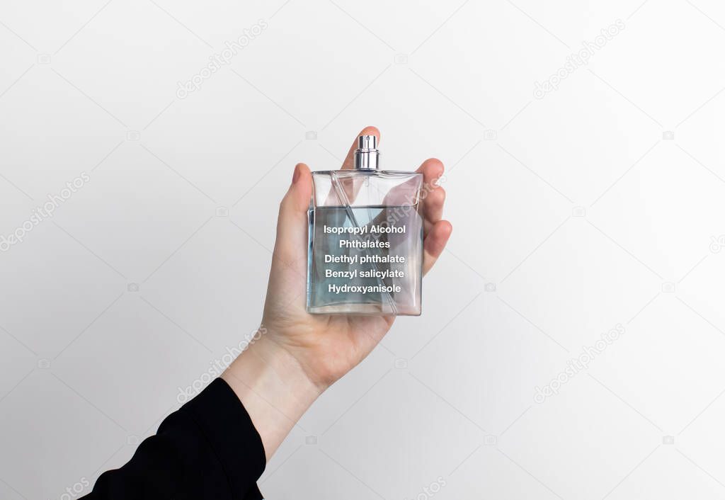 The woman is holding a perfume. Hazardous substances are indicated on the eau de toilette label. The concept of harmful components in cosmetics and household chemicals