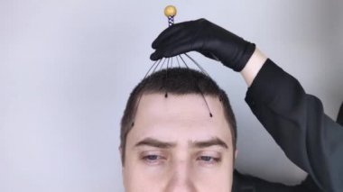 Bir adama kuaförde kılcal masaj aleti ile kafa masajı yapılır. Müşterinin yüzü rahatlama ve neşe gösteriyor. Stres önleyici masaj konsepti ve bir masörün sunduğu hizmetler..