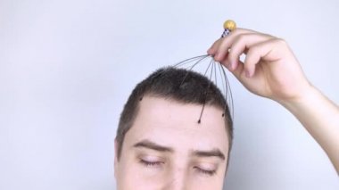 Beyaz arka plandaki bir adam kılcal masaj aleti ile kendisine masaj yapıyor. Kişisel gelişim, anti-stres ve rahatlama kavramı