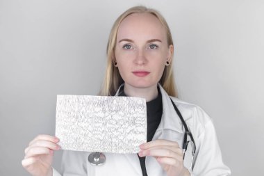 Bir nörolog hasta beyninin ensefalogramını inceler. Epilepsi belirtileri ve sinir sisteminin patolojileri için beyin akımlarını inceleyen elektroensefalogramların programı.