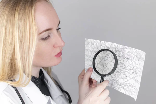 A neurologist with a magnifying glass examines an encephalogram of a patients brain. Schedule of electroencephalograms study of brain currents for signs of epilepsy and pathologies