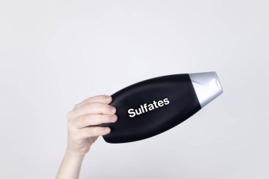 Chemical components on the shampoo label: Sulfates. Female hands hold the jar on which indicates the harmful ingredient. White background, place for your text clipart