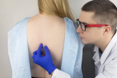 Doktor randevusunda sırt ağrısı olan bir kadın. Omurga deformasyonu ve boyun eğme tedavisi. Kemik erimesi, kifoz, lordosis veya skolyoz..