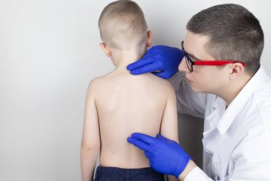 Doktor randevusunda sırt ağrısı olan küçük bir çocuk. Omurga deformasyonu ve boyun eğme tedavisi. Kemik erimesi, kifoz, lordosis veya skolyoz..