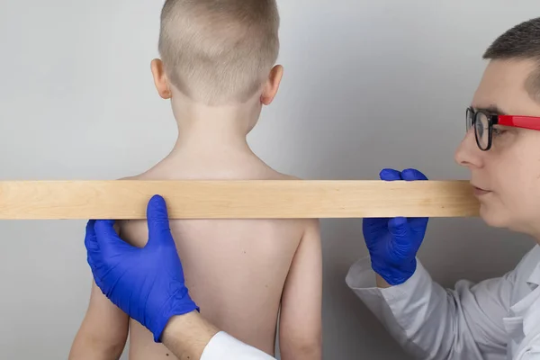 A little boy at the doctor's appointment with back pain. Treatment of spinal deformity and stoop. Osteoporosis, kyphosis, lordosis, or scoliosis.