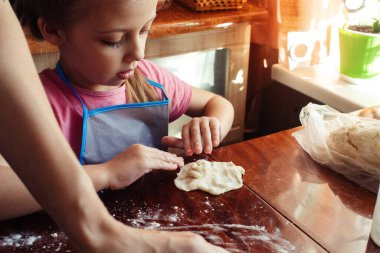 Küçük kız hamurla çalışıyor. Pizza yapmak ya da ev yapımı kurabiyeler. Karantina ve kendini tecrit sırasındaki dersler. El ve hamura yakın çekim