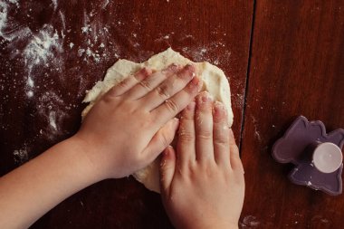 Küçük kız hamurla çalışıyor. Pizza yapmak ya da ev yapımı kurabiyeler. Karantina ve kendini tecrit sırasındaki dersler. El ve hamura yakın çekim
