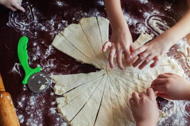 Anne ve çocuklar, izolasyon ve karantina sırasında mutfakta hamur hazırlıyorlar. Bir kadının elleri, bir oğlan ve un içinde bir kız yakın plan hamur yakınında. Mutlu bir aile ve birlikte yemek yapma kavramı.