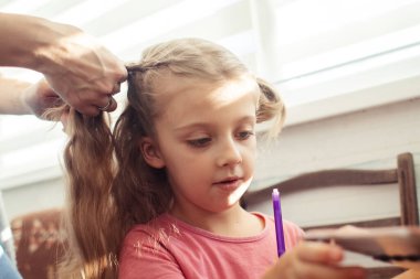 Annem kızının saçını tarıyor. Bebeğin saçına bakıyorum. Mutlu bir çocukluk ve çocuklara karşı iyi bir tutum. Mutlu aile