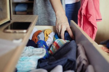 Bir kadın kendi gardırobundaki şeyleri elleriyle düzenliyor. Yıkandıktan sonra katlamak. Ev sorumlulukları, daireyi temiz ve düzenli tutmak.