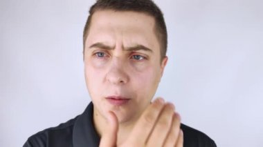 Bir adam aynanın önünde duruyor ve göz kapağının üst kısmındaki iltihabı görüyor. Gözlerinin etrafındaki cilt kırmızısı ve kanama..