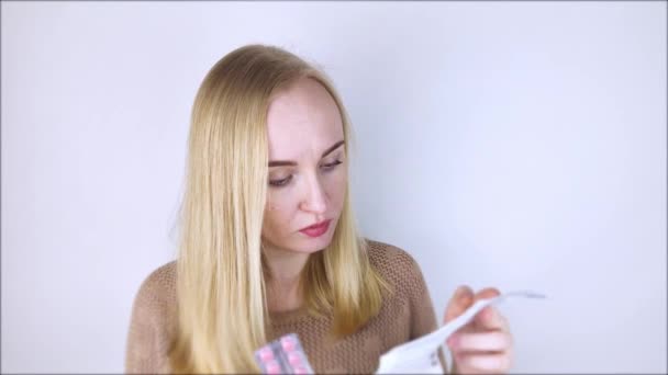 白色背景的女孩读药品说明书 这个女人看了看毒品的清单和成分 家庭自行用药的概念与药物特性的研究 — 图库视频影像