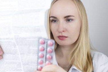 Beyaz arka plandaki doktor ilaçların talimatlarını okur. Uzman listeye ve ilacın bileşimine bakıyor. Profesyonel tedavi randevusu kavramı