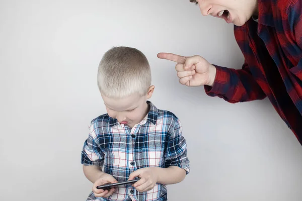 Dad tries to take the child\'s phone, on which he plays for a long time. The guy does not give up his smartphone and behaves aggressively. Child addiction to mobile phones and video games.