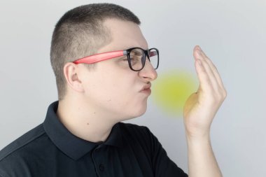 Nefesi kokan bir adam kameraya bakar. Kötü kokulu konsept. Ağzından pis bir koku duyan birinin yakın çekimi. Mide sorunları, ağız temizliği, tütün kokusu, diyet yan etkileri.