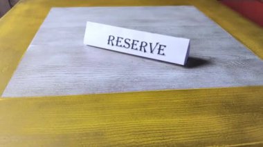 Tabağın etrafındaki uçuş rezervasyonu, restorandaki ahşap masanın üzerinde duruyor. Kafe 'de bir yer rezervasyonu. Koltuk rezervasyonu. Kurumda önceden bir masa ayırtmak.