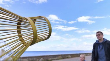 Baba ve oğul plastik şişeyi plastik toplama konteynırına attılar. Plastiğin geri dönüşümü ve imhası. Çocuklara temizlik ve düzen öğretme kavramı. Baba oğluna örnek olur.