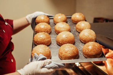 Fırıncı fırından taze pişmiş ekmek ve ekmek çıkarır. Ev yapımı kekler kapanıyor. Ev yemeği konsepti. Altın kabuklu yiyeceklerin yakın çekimi.