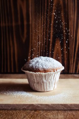 Tepside yakın plan muffinler. Pudra şekerli kek. Şekerleme endüstrisinin işi. Her kek kâğıt ambalaja sarılmış..